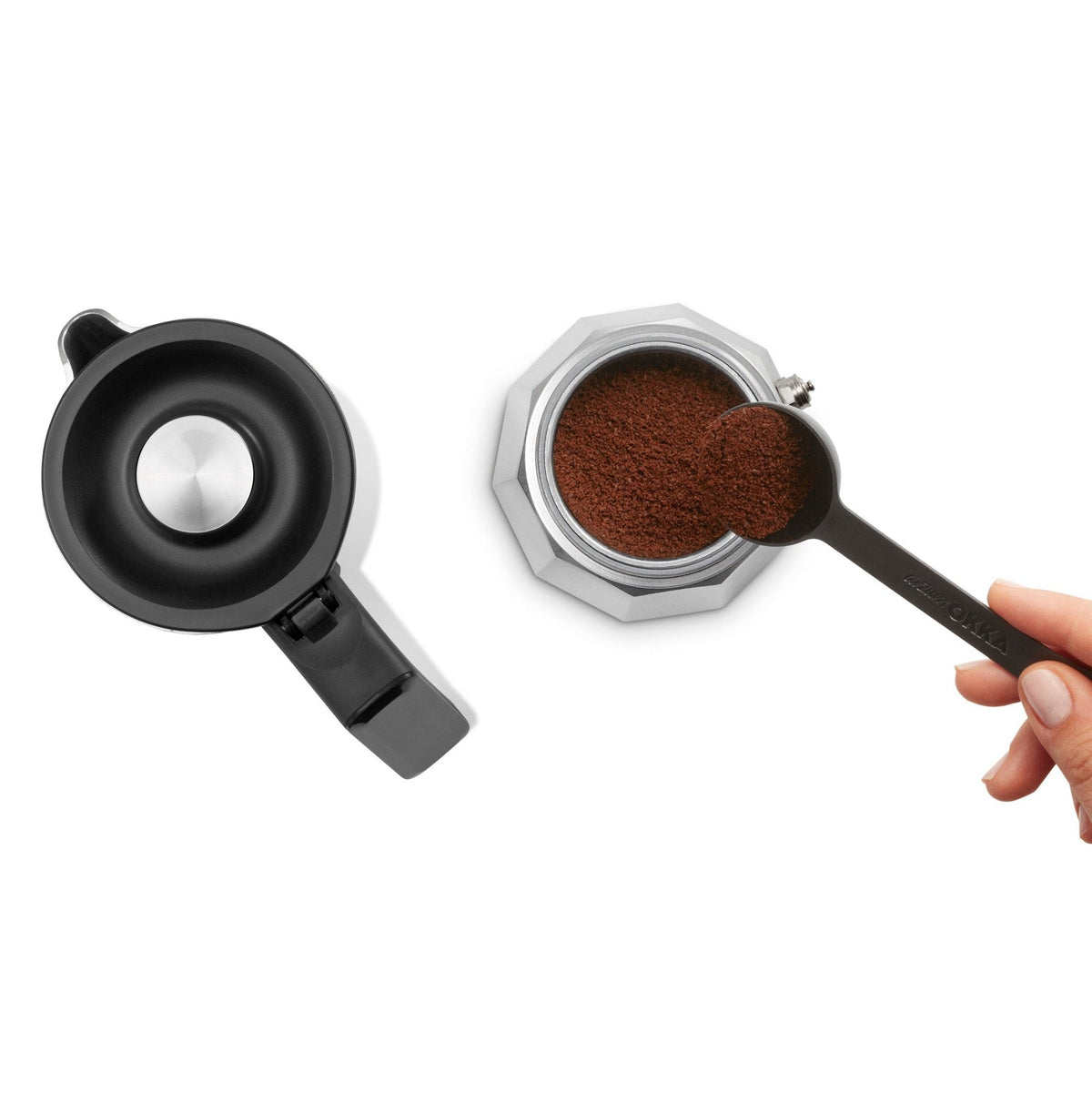 Coffee maker with a hand holding a scoop of ground coffee on a white background