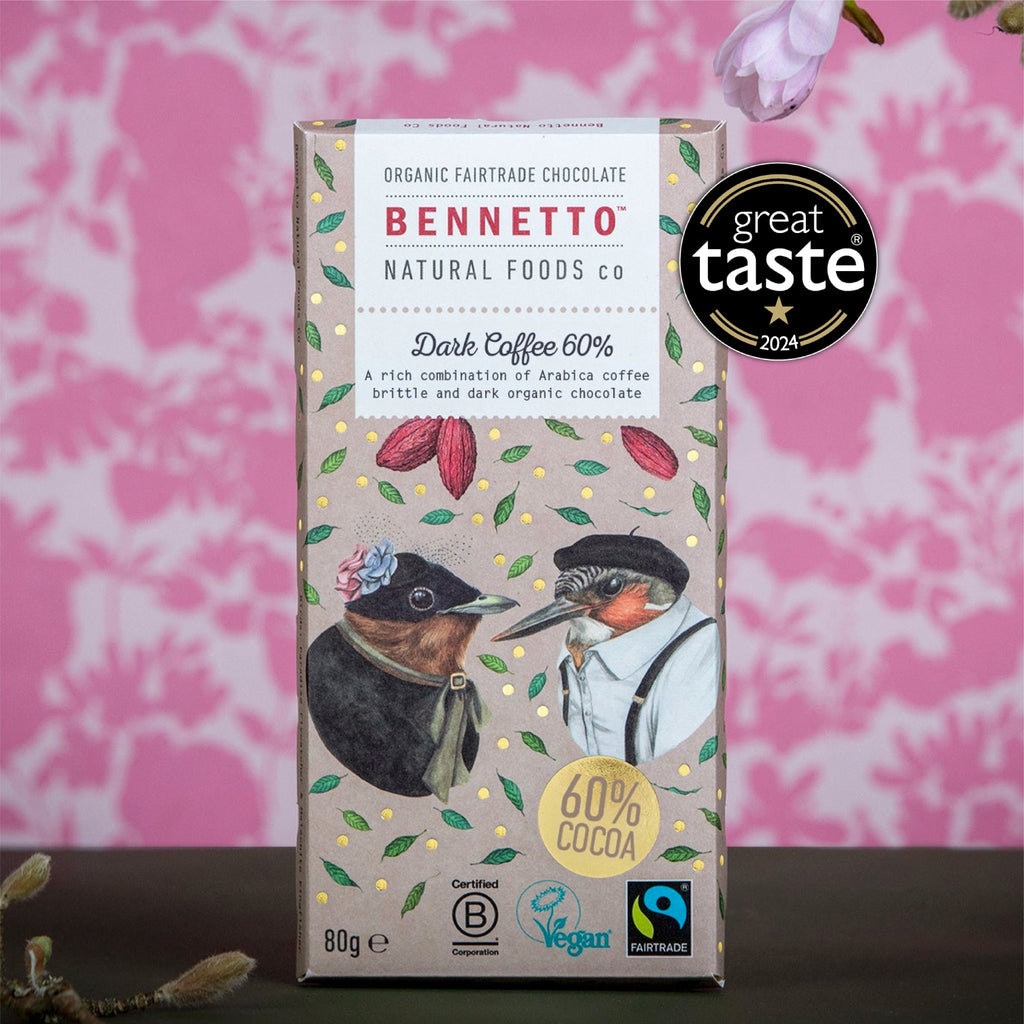 A boxed bar of Bennetto Natural Foods Co. Dark Coffee 60% chocolate is shown upright against a pink patterned backdrop.