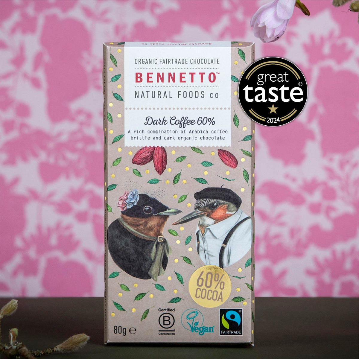 A boxed bar of Bennetto Natural Foods Co. Dark Coffee 60% chocolate is shown upright against a pink patterned backdrop.