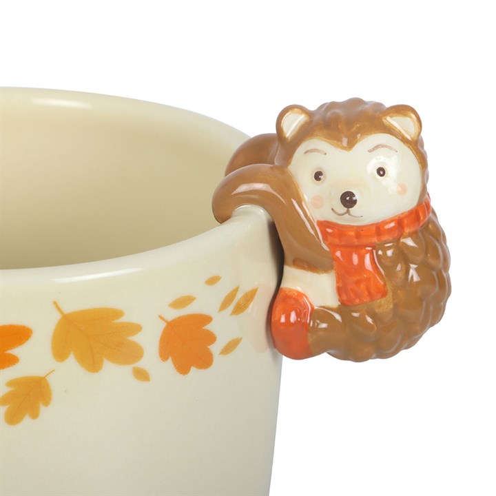Ceramic plant pot with a hedgehog handle featuring autumn leaf patterns on a white background