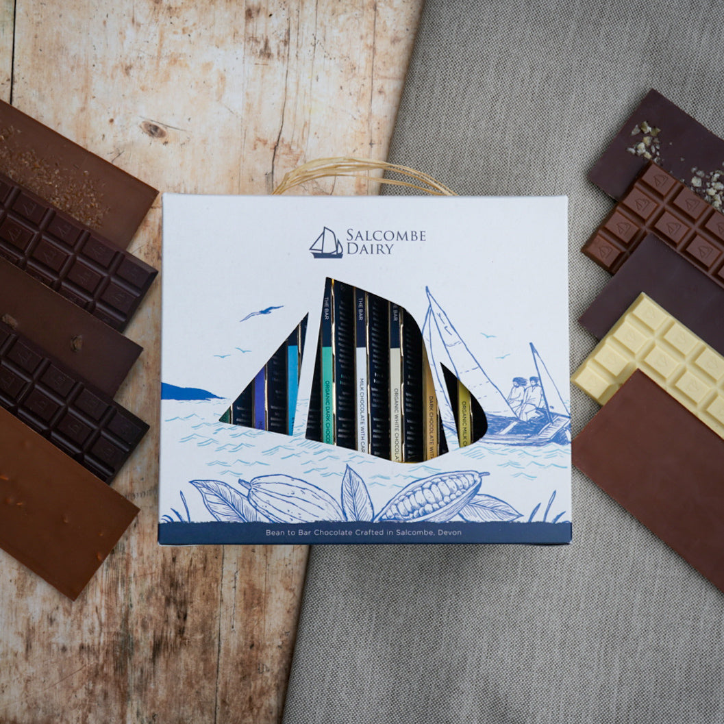 Salcombe Dairy chocolate box with various chocolate bars on a wooden and gray surface