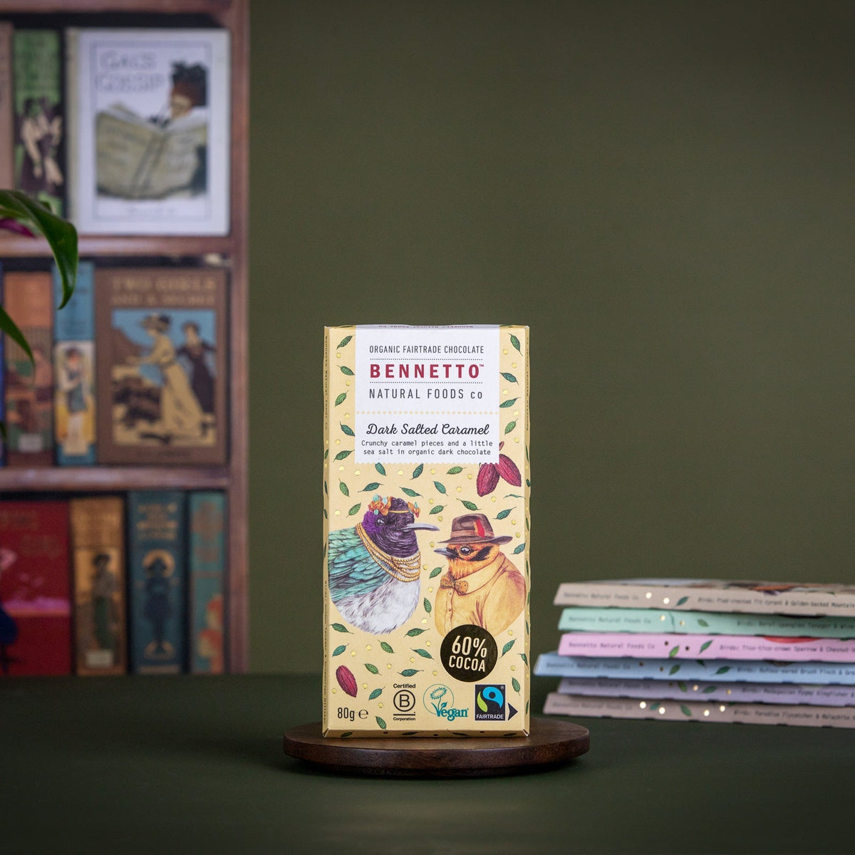 Chocolate bar packaging on a wooden stand with books and a plant in the background
