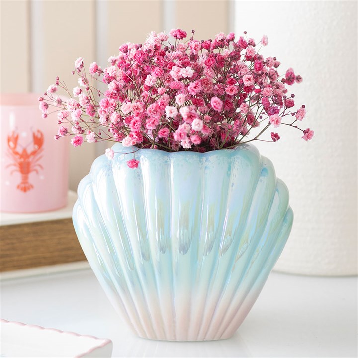 Shell-shaped vase with pink flowers on a light background