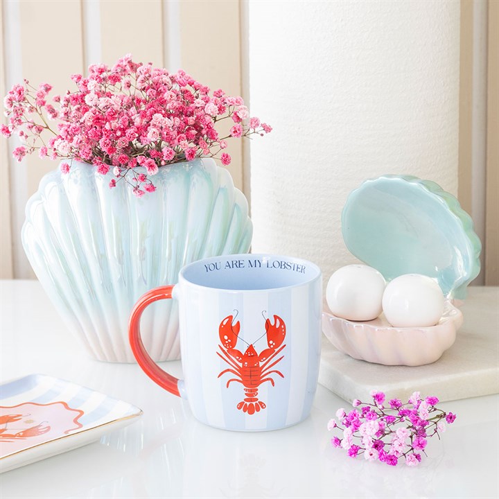 Plant vase on a table with flowers and decorative items.