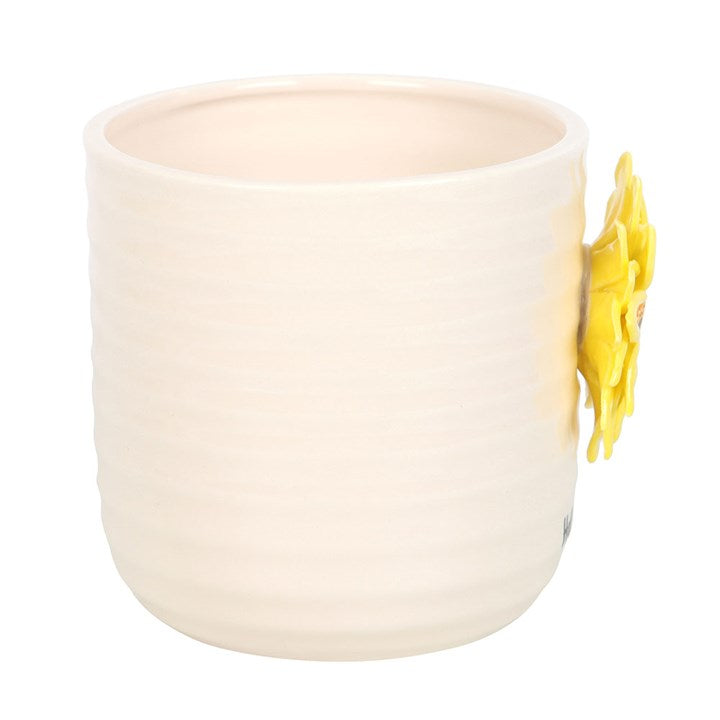 White ceramic plant pot with a yellow flower on a white background