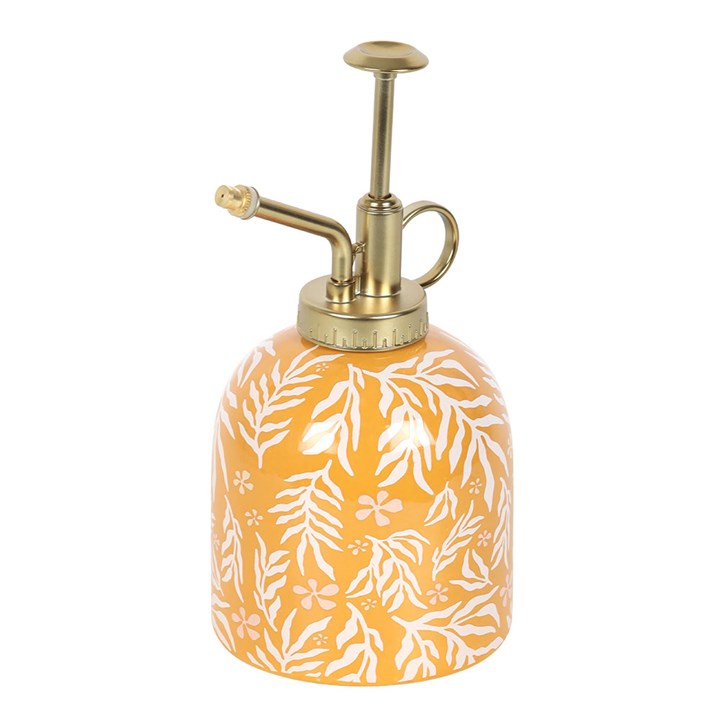 Decorative spray bottle with gold nozzle and white leaf pattern on orange background