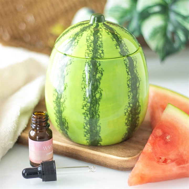 Watermelon-themed container with a bottle of essential oil on a wooden board.