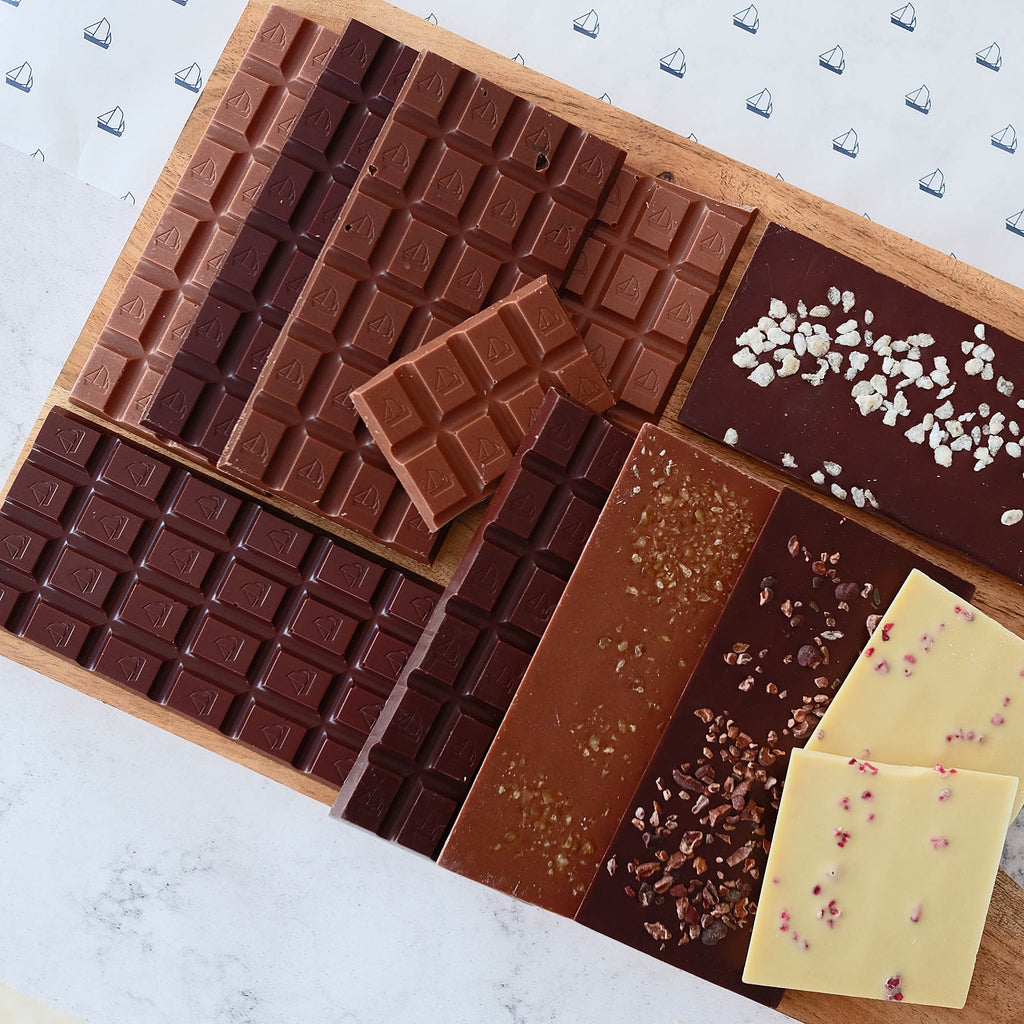 Assorted chocolate bars on a wooden board with a light background