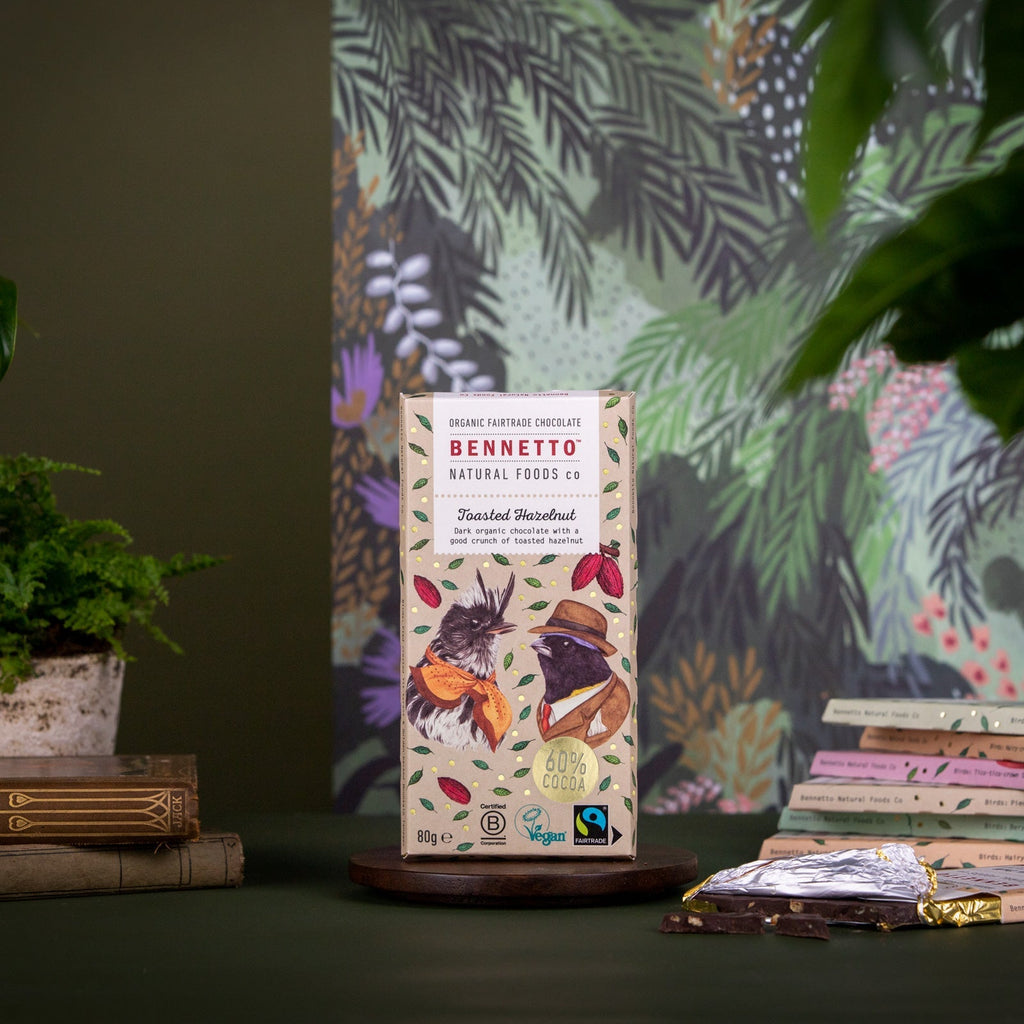 Bennetto natural foods co chocolate bar packaging on a dark surface with a colorful plant-themed backdrop