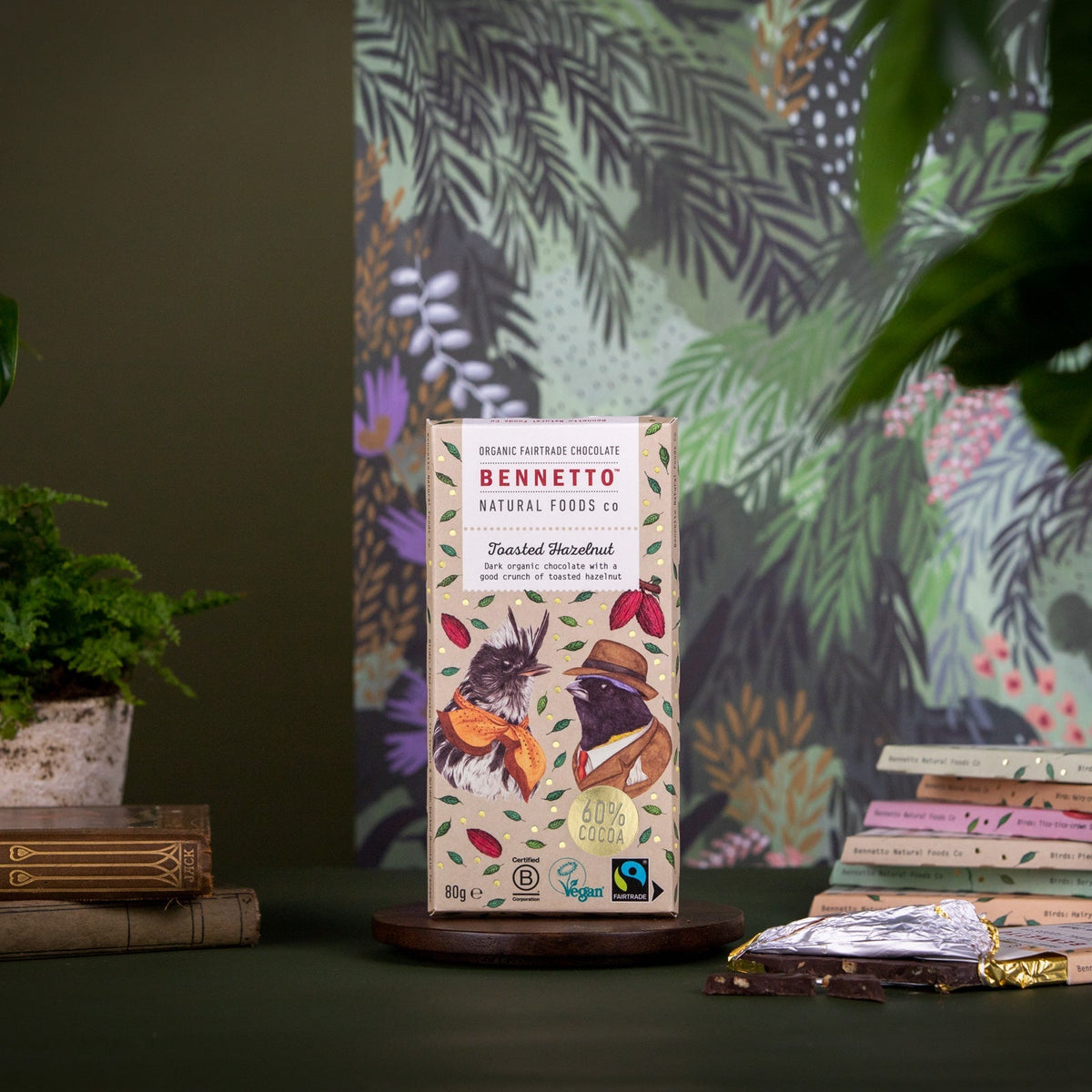 Bennetto natural foods co chocolate bar packaging on a dark surface with a colorful plant-themed backdrop