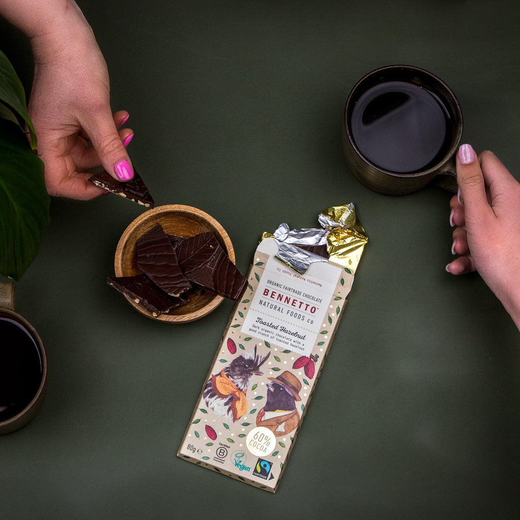 Bennetto chocolate bar with a cup of coffee and a bowl of chocolate on a dark surface.